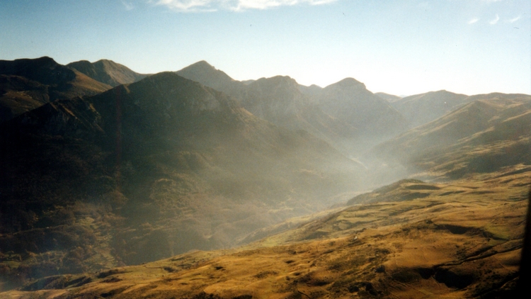 Blauer Himmel, braune Berge im Gegenlicht; eine nebelbehangene Schlucht